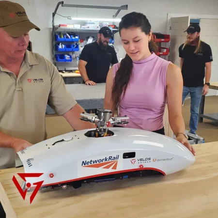 Velos Rotors' Amaryllis, UAV Engineer Intern, examines components of a Velos V3 aircraft with team members.