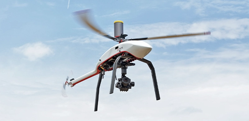 White Velos V3 unmanned helicopter flying under clear blue sky